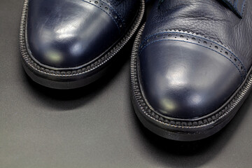 Dark blue men's boots made of genuine leather, with on a black background, beauty and fashion,