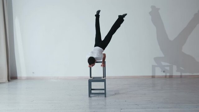 The acrobat keeps balance on the chairs. Acrobatic number without insurance