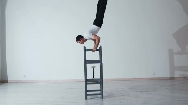 The acrobat keeps balance on the chairs. Acrobatic number without insurance
