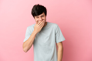 Young Russian man isolated on pink background happy and smiling covering mouth with hand