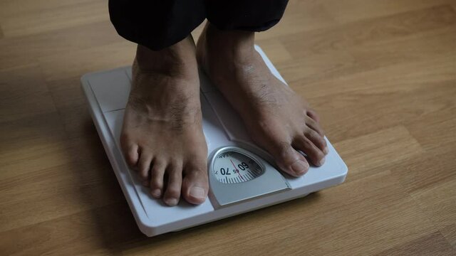 Asians foot man with body weight scales for measure weight loss.Weighing scale to healthy slimming concept.medium long shot panning dolling shift focus dolly slider for slow motion
