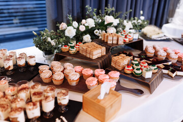 candy bar decorated by delicious sweet buffet with cupcakes, eclairs, sweetness and flowers, and other desserts, candy, Dessert table for a wedding or birthday party.
