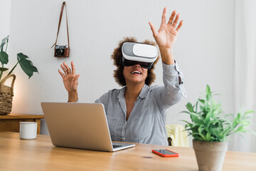 Senior african woman using virtual reality headset at home office - Technology business trend and lifestyle concept - Focus on vr goggles