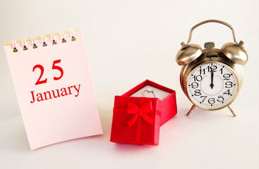 calendar date on light background with red gift box with ring and alarm clock with copy space. January 25 is the twenty-fifth  day of the month