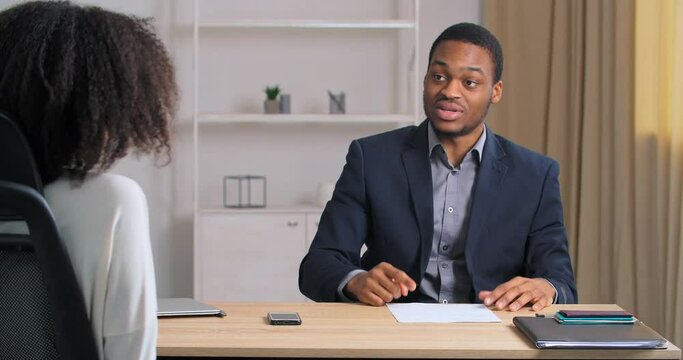 Emotional afro american business man worker sitting at office feeling angry upset actively gesticulating explaining speaks loudly expresses opinion idea of sartup project for unmanageable female boss