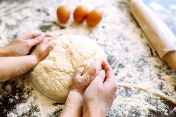 Hands of mother and son kneading a dough together.  Family cooking at home. Easter baking preparation. Cookies for Christmas.