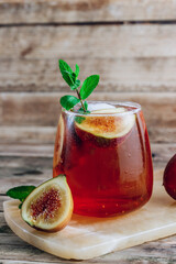 Cold lemonade cocktail with figs on rustic wooden background