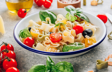 Heart pasta salad with colorful tomatoes, olives, parmesan and basil leaves