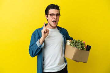 Russian Man making a move while picking up a box full of things isolated on yellow background...