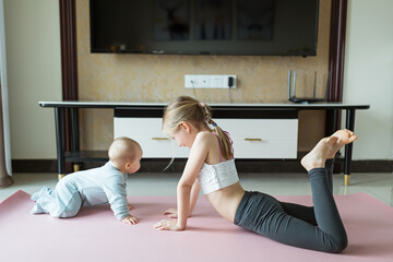 Cute little girl in sportswear doing fitness exercises at home. Distant training with personal trainer, social distance or self-isolation, online education concept