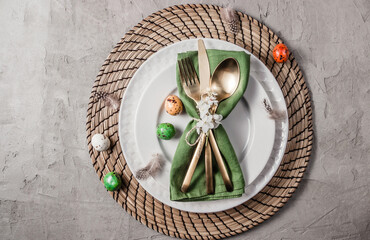 Easter table setting. Empty plates with green linen napkin and golden cutlery on concrete background. Top view. Flat lay. Copy space.