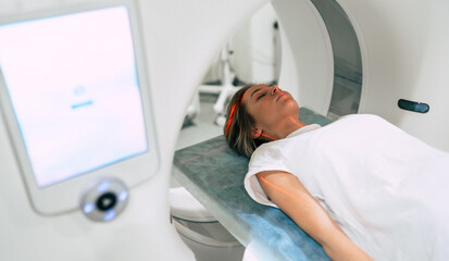 Young woman patient is ready to do magnetic resonance imaging in the modern hospital laboratory - obrazy, fototapety, plakaty