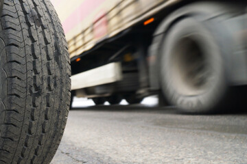  A stationary car wheel against the background of a fast moving trailer. Speed concept. An example of contradistinction is immobility and movement.