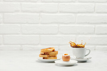 Coffee splash from a cup with breakfast on white table