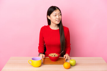 Young Chinese girl  having breakfast in a table looking side