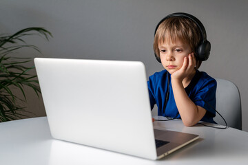 A boy in front of a computer in headphones.