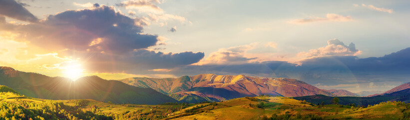 Naklejka na ściany i meble mountainous rural panorama landscape in springtime at sunset. beautiful scenery beneath a sky with clouds in evening light. grass covered hill rolling in to the distant ridge