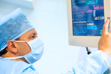 Doctor cheking patient's vital sign at monitor in operating room.