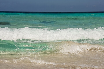 wave breaking at the sand beach, beautiful turquoise water lagoon, sunny blue sky
