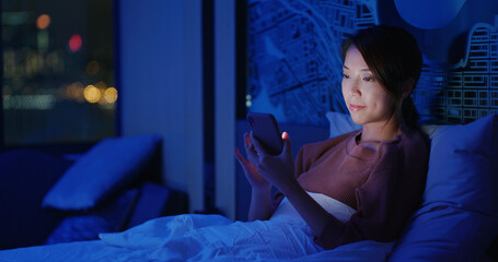 Woman use of mobile phone on bed at night