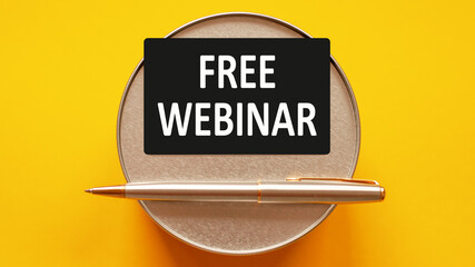 free webinar - word on a black sheet on a yellow background with round metal stand and metal writing pen, business, finance and education concept