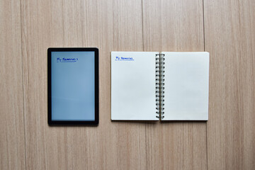 a tablet and notebook on wood table,old and new style of technology to note and take a memo for note or lists concept