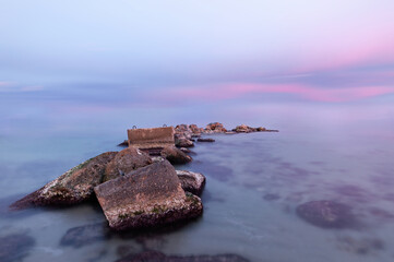 Sunset on the beach of Aguamarga, Alicante. Pastel colors of a sunset on the beach with sea rocks of protagonists in the foreground. Perfect for background.