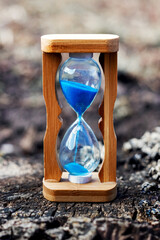 Hourglass on an old rotten stump. The concept of ancient times