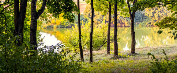 Autumn landscape with trees by the river in early autumn. Panorama
