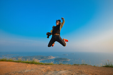 Asian traveler man jumping on a top of mountain view point with happiness on beautiful sea view , phuket Thailand, The beautiful sea viewpoint of sea and island from a top of mountain in summer