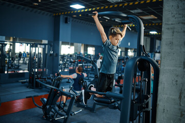 Fototapeta na wymiar Boy on exercise machine, fitness training in gym