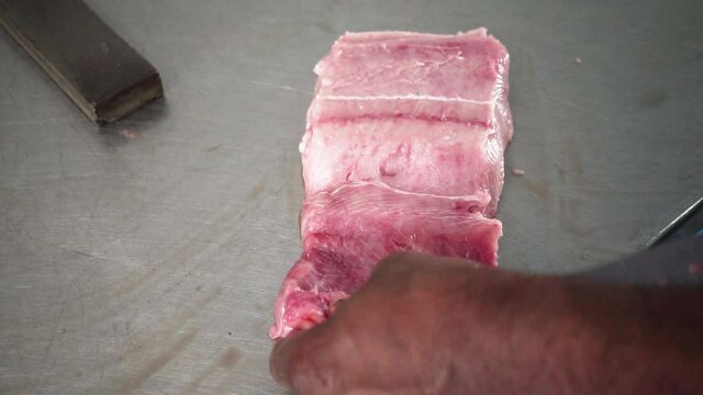 Close-up of hands slicing red fish fillets on a wooden cutting board, Afroamerican Male hands cutting fresh meat