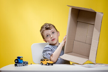 Surprised boy looking opening a box and gasping in surprise seeing the content of the box while recording an unboxing vlog