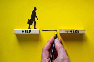 Help is here symbol. Wooden blocks with words 'Help is here' on beautiful yellow background....