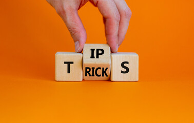 Tips and tricks symbol. Businessman turn the wooden cube and changes the word 'tips' on 'tricks'....