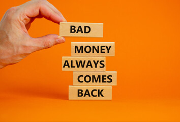Business concept growth success process. Wood blocks on orange background, copy space. Businessman hand. Words 'bad money always comes back'. Conceptual image of motivation.