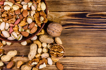 Various nuts (almond, cashew, hazelnut, pistachio, walnut) in ceramic plate on a wooden table. Vegetarian meal. Healthy eating concept. Top view