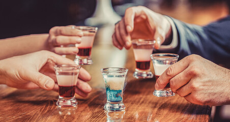 Group friends tequila shot glasses in bar. Male hands glasses of shot or liqueur. Friends drink shot or liqueur. Five glasses of alcohol