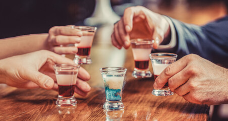 Group friends tequila shot glasses in bar. Male hands glasses of shot or liqueur. Friends drink...