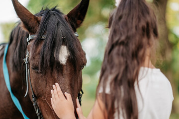 Emotional contact with the horse. Horse riding. The girl rides a horse in the summer.