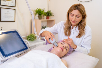 Woman in a spa salon on cosmetic procedures for facial care. Beautician makes medical procedures...