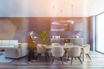 Businesswoman wearing formal suit is drinking tea at cozy kitchen