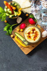 Arabic Cuisine. Middle Eastern Hummus with snacks. Hummus dip with fresh vegetables sticks on a dark stone countertop. Top view. Flat lay. Copy space.