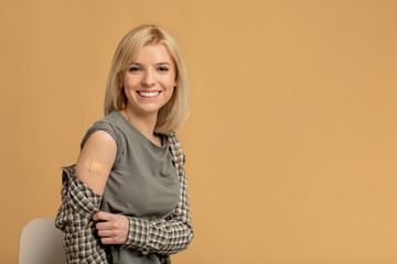 Virus protection. Excited vaccinated woman showing arm after injection, studio background with free...