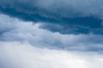 Cumulus clouds, navy blue bad weather sky, thundercloud and beginning of heavy rain at summertime