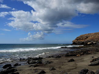 Fototapeta na wymiar Rocks and sand beach, blue sky and clouds, coast of Jandia, Fuerteventura, Canary Islands, Spain