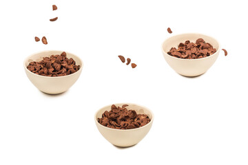 Chocolate corn flakes falling to the white bowl isolated on white. Motion.