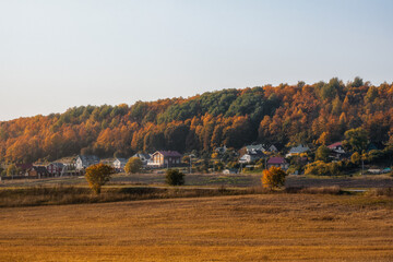 Sunny evening landscape with farmland ready for planting, with a village on a hill in the autumn background