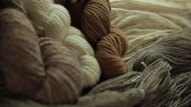 Zoomed in video showing fruitful results of wool making process, dyed yarn of different shades are stacked neatly in together in groups. 