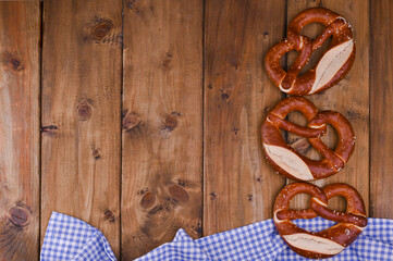 Bavarian pretzel decorated with a blue and white cloth on a rustic wooden board - Munich Oktoberfest. Background and free space for text. Traditional pastries for the festival